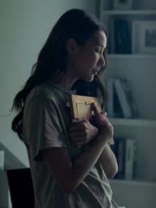 Asian lady holding picture in darkened room