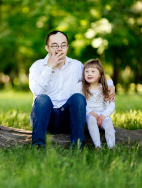 Man and young girl sitting on log on a sunny day