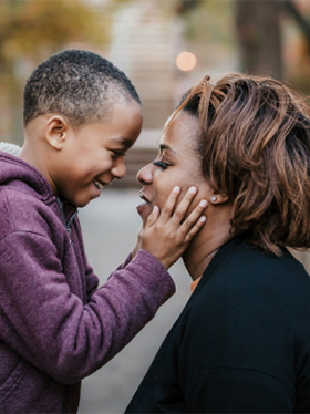 Boy happily cupping lady's face in his hands
