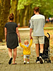 Young couple walking in park with toddler