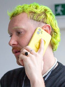 Young male with bright yellow hair, speaking on mobile phone